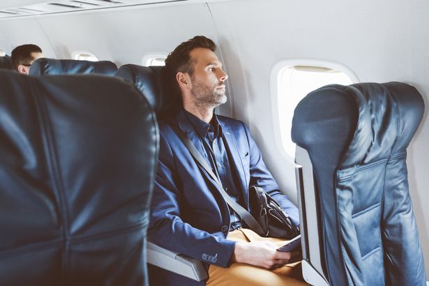 Mature man sitting in airplane seat near window. Business man flying by plane.