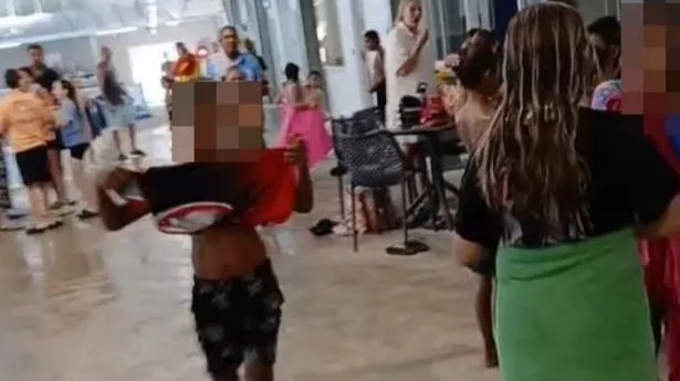 A roup of children (blurred faces) standing by a pool