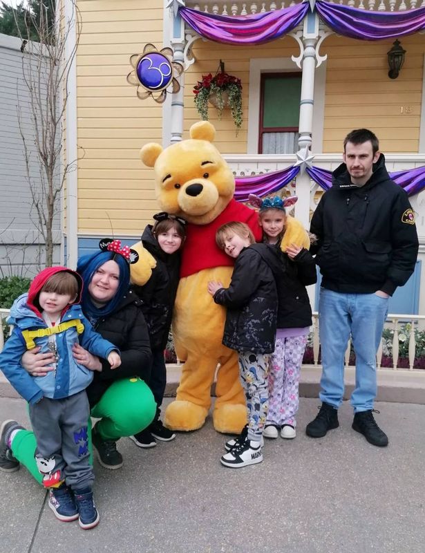 Photo of cancer patient Ashleigh Ellerton and her family standing next to a large Winnie the Pooh mascot in Disneyland