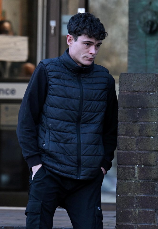 Man in dark puffer vest and cargo pants outside a brick wall.