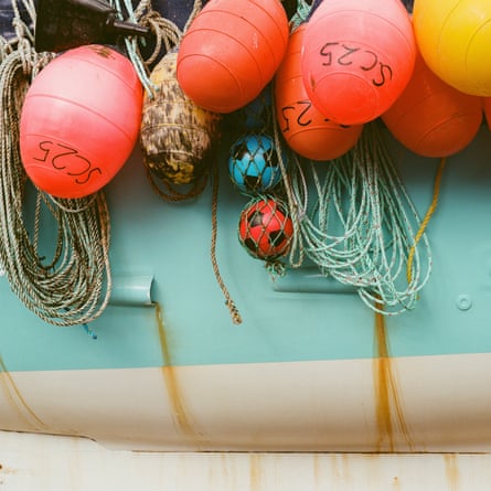 Footballs in nets among a string of boat bumpers.