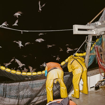 Two fishers hauling in a net 