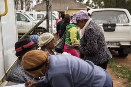 African women filling in forms as they wait in a queue