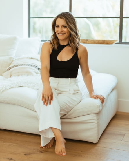 a woman in a black top and white trousers sitting on a white sofa