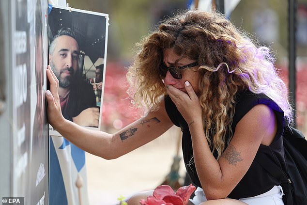 A woman reacts next to a portrait at the memorial site for the victims of the October 7 massacre on the eve of the anniversary, October 6, 2024, near Kibbutz Re'im