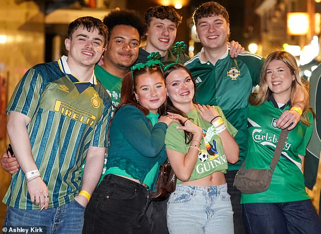 A group of friends in green sports shirts and shamrocks strike a pose in Nottingham city centre