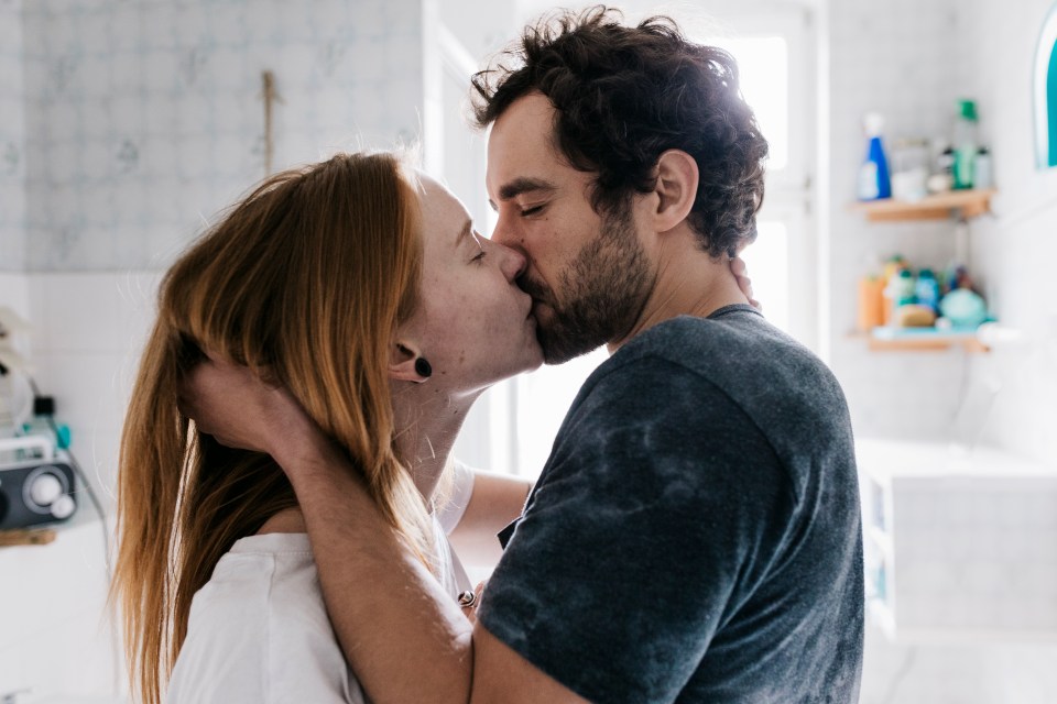 Couple kissing in a bathroom.