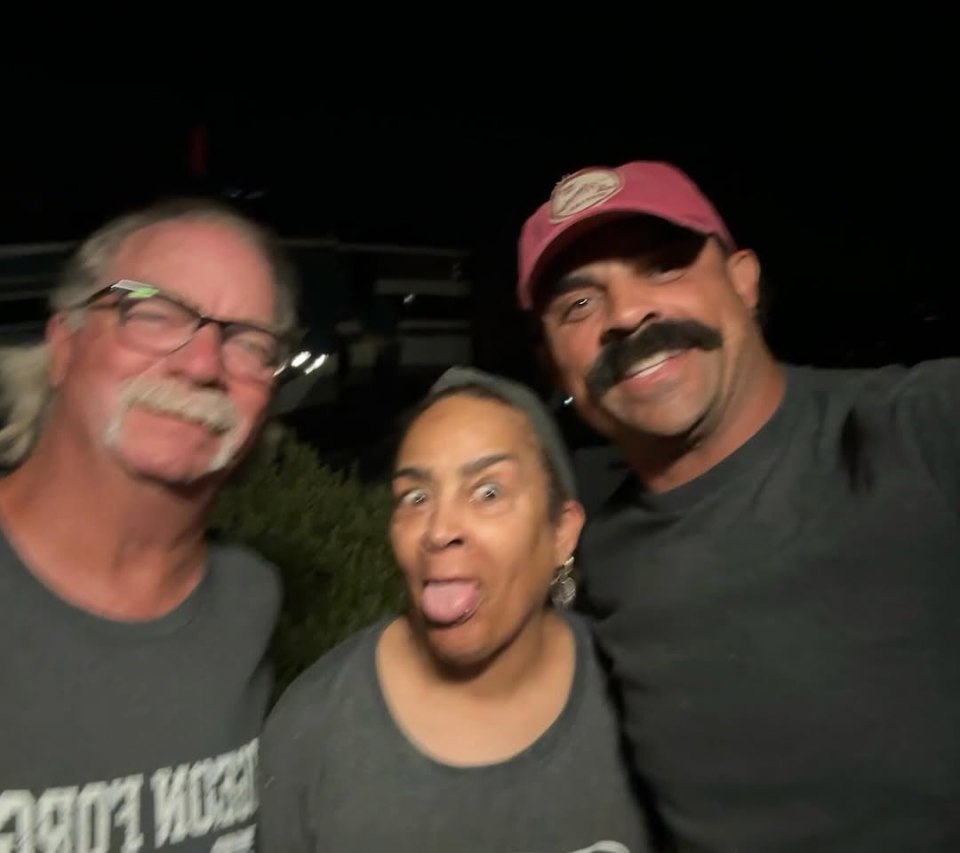 Three people posing for a photo at night.