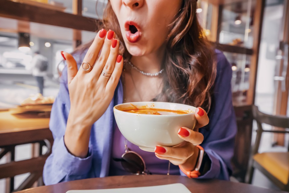 Woman reacting to spicy Tom Yum soup.