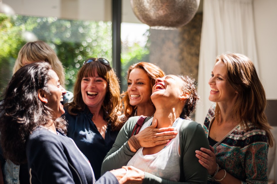 Group of women laughing together at a reunion.