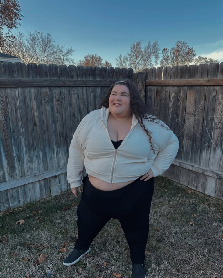 Plus-size woman in cream zip-up top and black leggings.