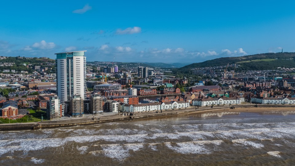 Aerial view of Swansea Bay, showing the city skyline, beach, and waves.