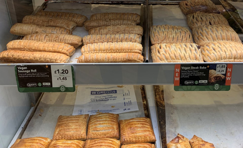 Vegan sausage rolls and steak bakes in a bakery display case.