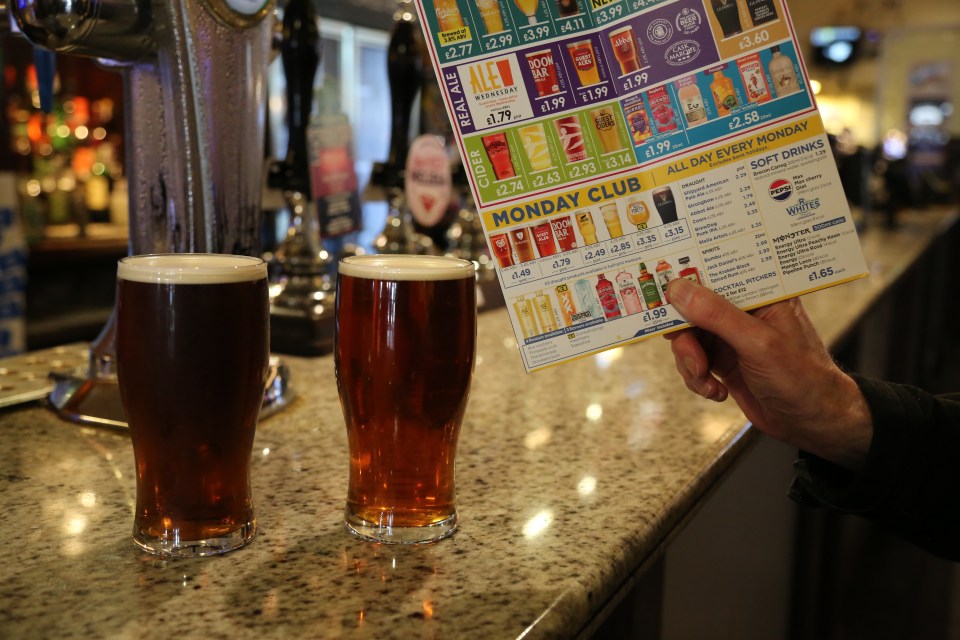 Person looking at pub menu with two pints of beer on the bar.