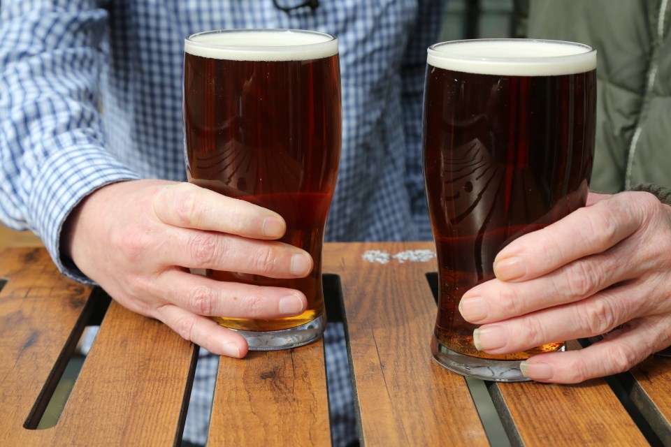 Two pints of beer on a wooden table.