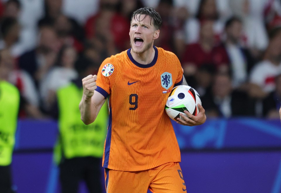 Wout Weghorst of the Netherlands celebrates a victory, holding a soccer ball.