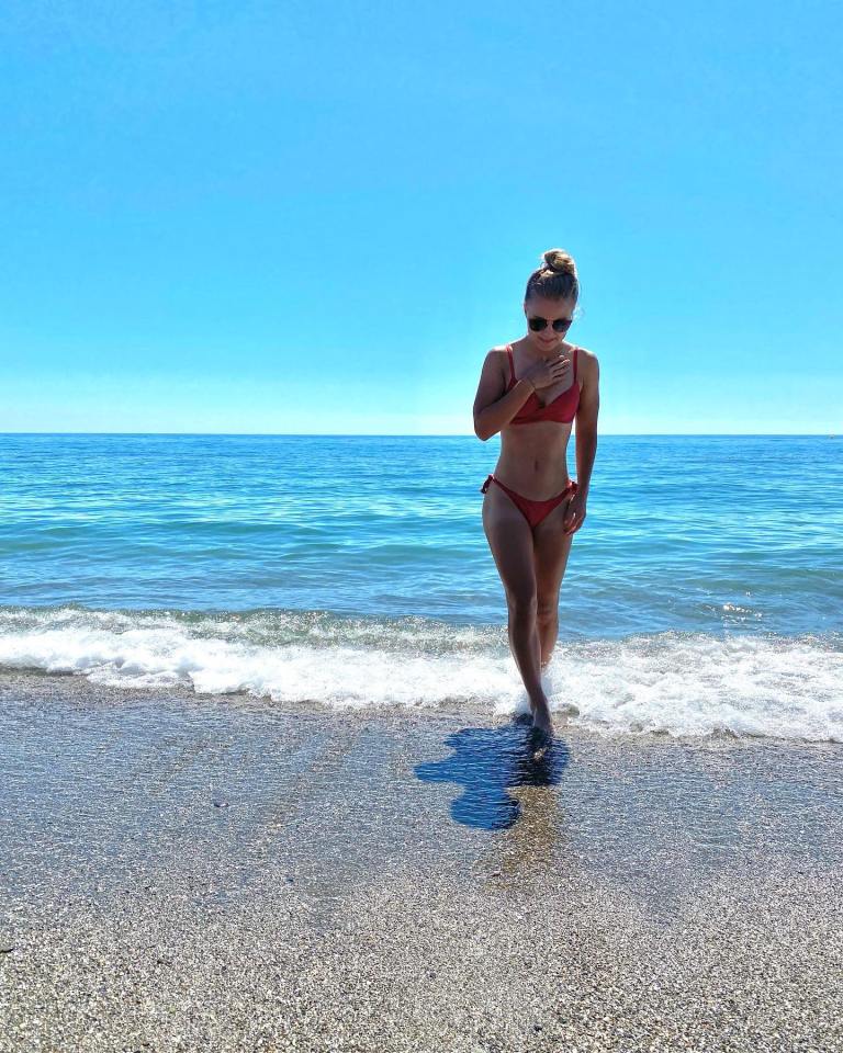 Woman in red bikini walking on beach.