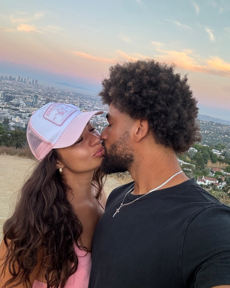 Couple kissing with city skyline in background.