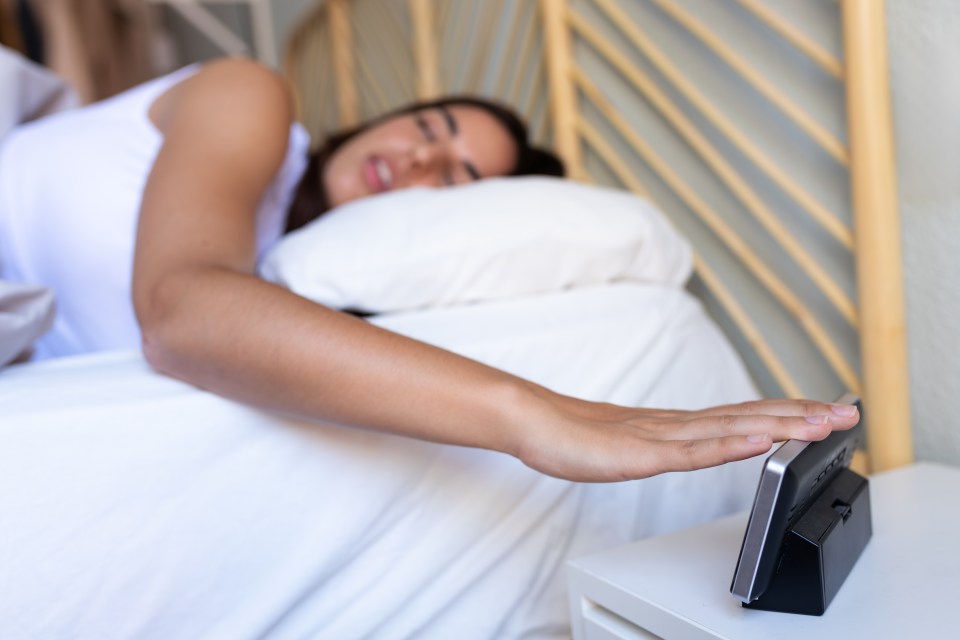 Woman's hand turning off alarm clock.