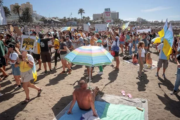 Protesters march on Las Americas beach during a demonstration to protest against mass tourism,