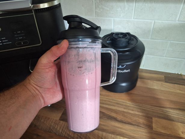 Blender and a pink smoothie pictured in a kitchen
