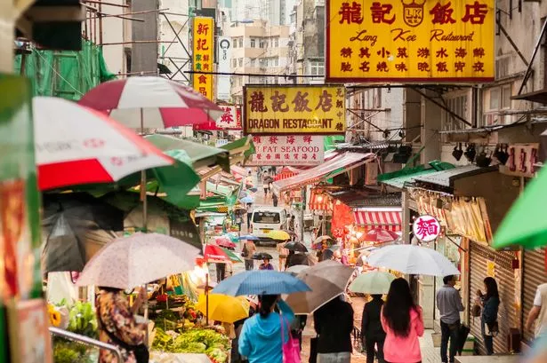 Hong Kong iStockalypse. Shoppers with umbrellas walk through a busy outdoor food market in Sheung Wan District, Hong Kong, China