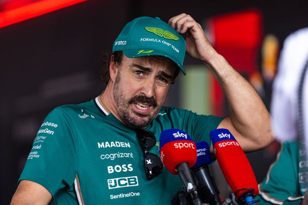 Fernando Alonso scratches his head as he speaks into a Sky Sports microphone