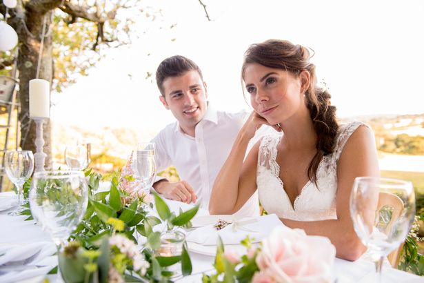 Bride looks annoyed as groom comforts her