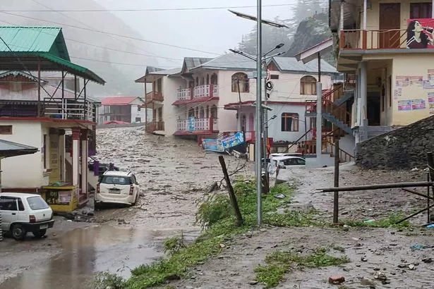 Muddy water running past residential buildings following a massive mudslide in India's Uttarakhand state