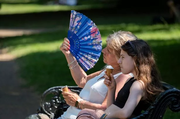 People having an ice cream and using a fan to keep cool in Hyde Park enjoying and enduring the first Summer heatwave of the year on 30th July 2024 in London, United Kingdom