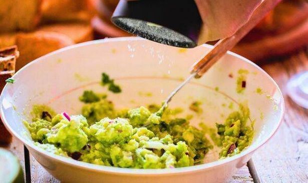 Picture of someone adding salt to guacamole