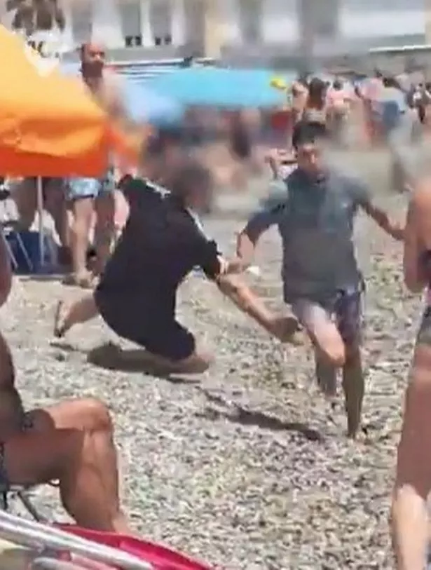 A man appears to be reaching to grab the ankle of one of the runners