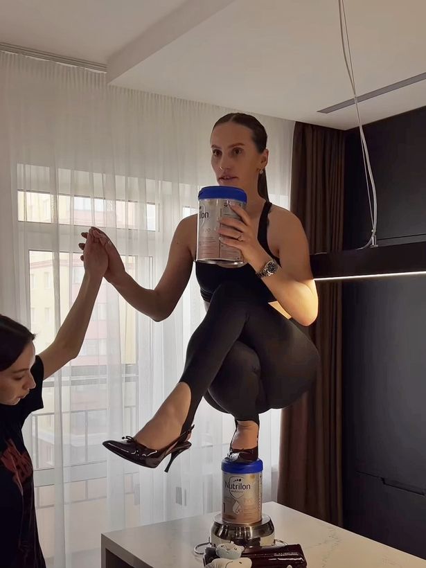 Mariana Barutkina trying to balance on a bottle of baby formula in her heels