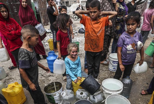 Palestinians, including children, wait in line to fill water canisters
