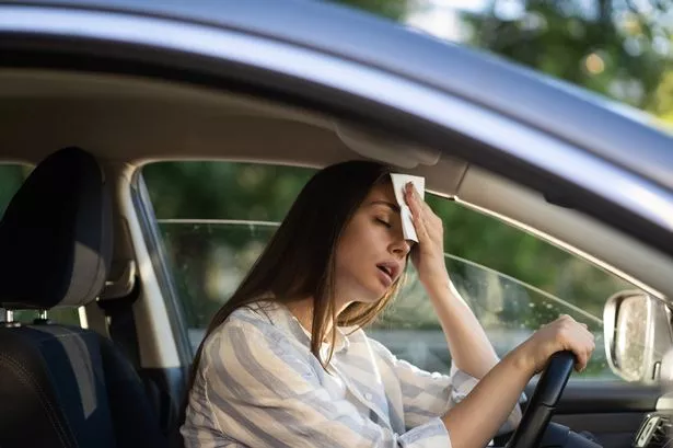 Female driver wiping forehead