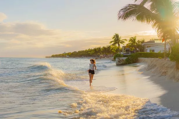Young Caucasian woman running happily on the beach in Tulum, Mexico