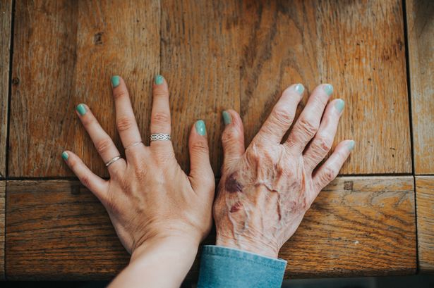 Young hand and old hand, beside each other, wearing matching green/blue nail polish.