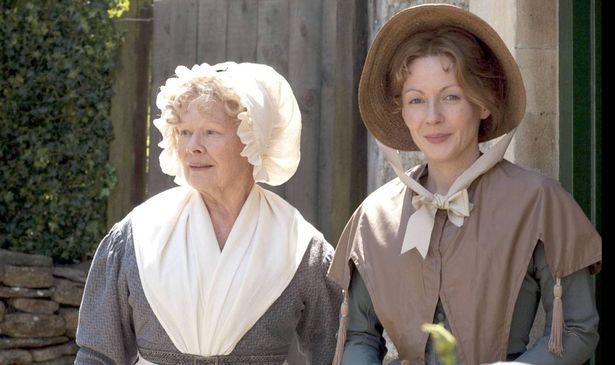 Two women in bonnets stand outside a house