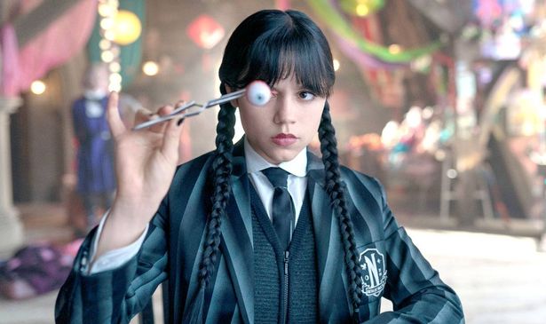 A girl holds up an eyeball with tweezers
