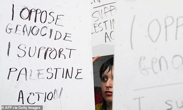 Protesters hold up hand-written signs that read 'I oppose genocide, I support Palestine Action' during a demonstration in Parliament Square, London, on July 19