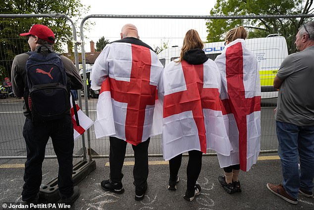 Hadush Kebatu was charged with sexually assaulting a schoolgirl just days after he arrived in Britain. Pictured: three protesters draped in English flags look through the protective fencing