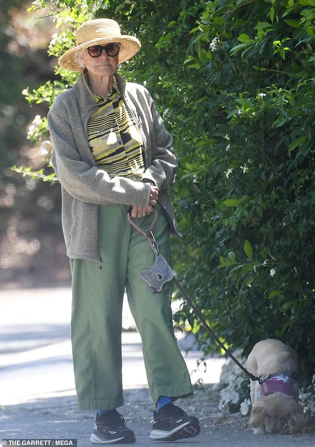 She kept things casual in a gray zip-up jacket, green pants, and black Hoka sneakers, topping off the look with a straw hat and black sunglasses