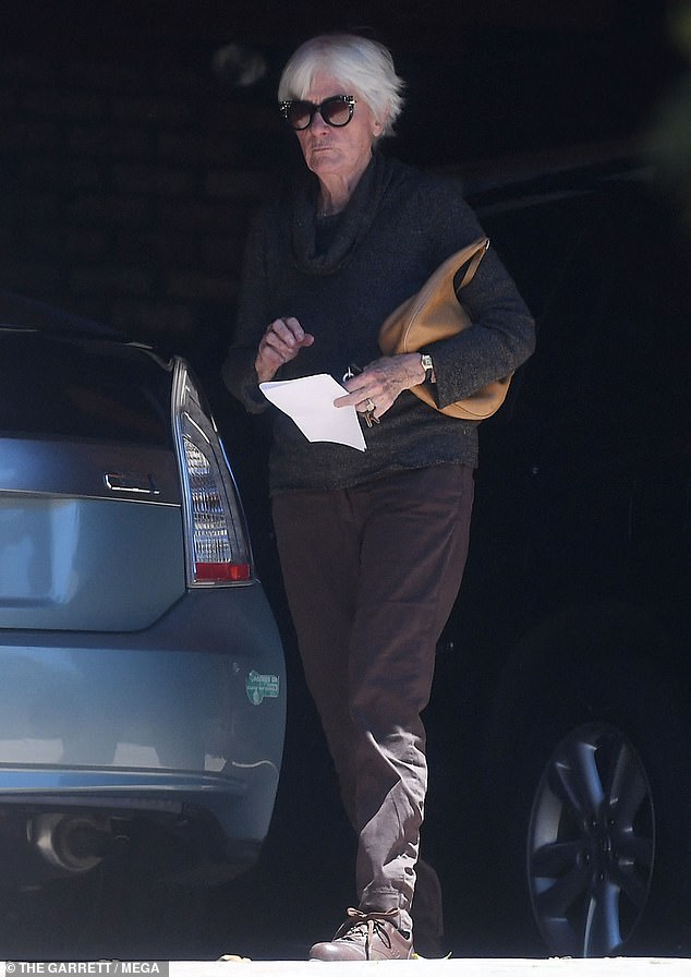 After her walk concluded, she emerged from her house and got in her blue Prius to run some errands. She wore an all-black ensemble consisting of a sweater, pants, brown Oxford shoes and had a tan purse clutched in her arm