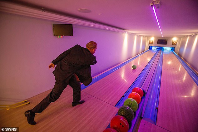 Graham Wildin inside the leisure centre he has built for himself and his family in his back garden, which includes a bowling alley (pictured)