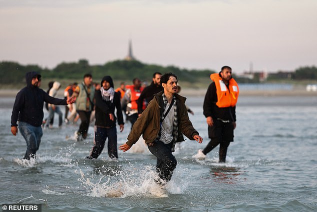 The Home Office has announced measures to get tough on smuggling gangs, despite more than 25,000 illegal arrivals so far this year. Pictured: A group of migrants run from the beach into the water to reach an inflatable dinghy near Calais, France, July 17