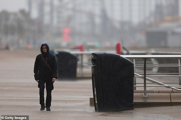 The Met Office has issued an amber warning for much of Scotland and a yellow warning for northern England. Pictured: A man walking in the rain in Blackpool