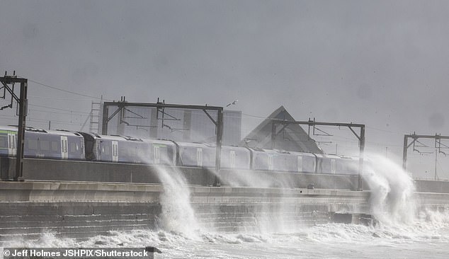 A train Arrives at Saltcoats station in Scotland as the sea wall is breached by sea Storm Floris