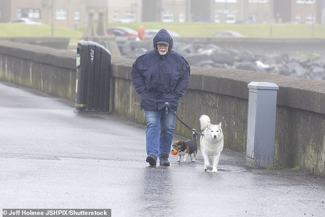 A man walks his dogs on the seafront in Saltcoats, Scotland, where there is an amber weather warning