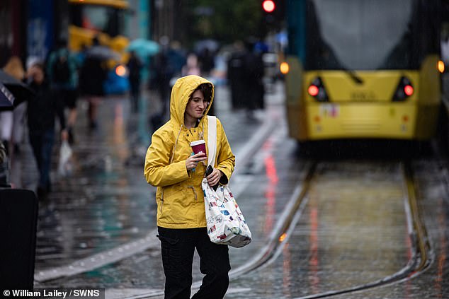 People in Manchester City Centre brave the morning commute through wind and rain this morning as they arrive at Picadilly Garden
