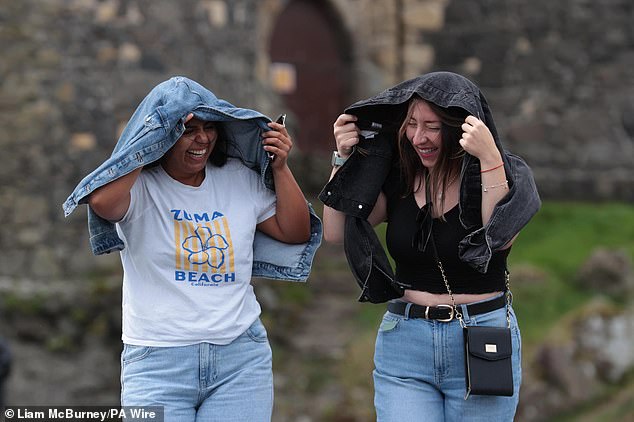 Giselle Munoz Alarcon (left) and Dominica Sepulveda Gutierrez shield from the wind at Carrickfergus Castle, County Antrim